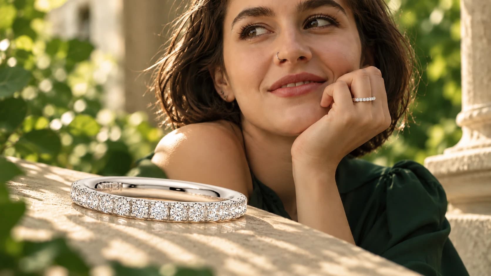 Smiling model wearing a diamond eternity band, the band resting in sunlight