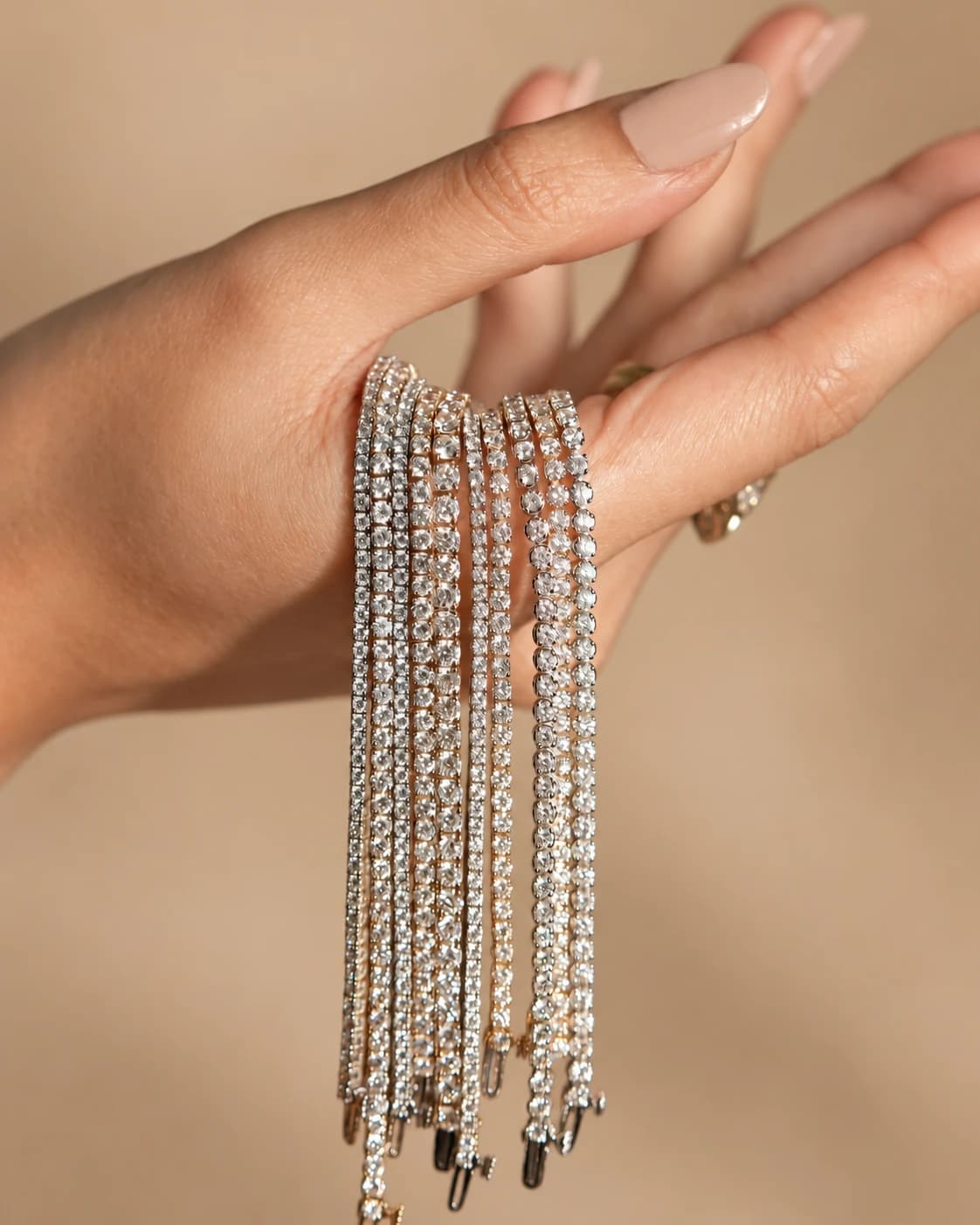 A hand holding a bundle of white and yellow gold diamond tennis bracelets