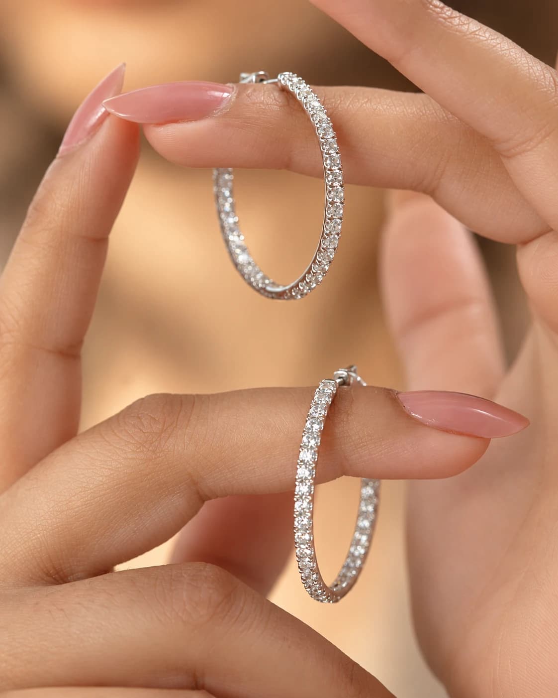 Pair of white gold diamond inside-out hoop earrings held between fingertips